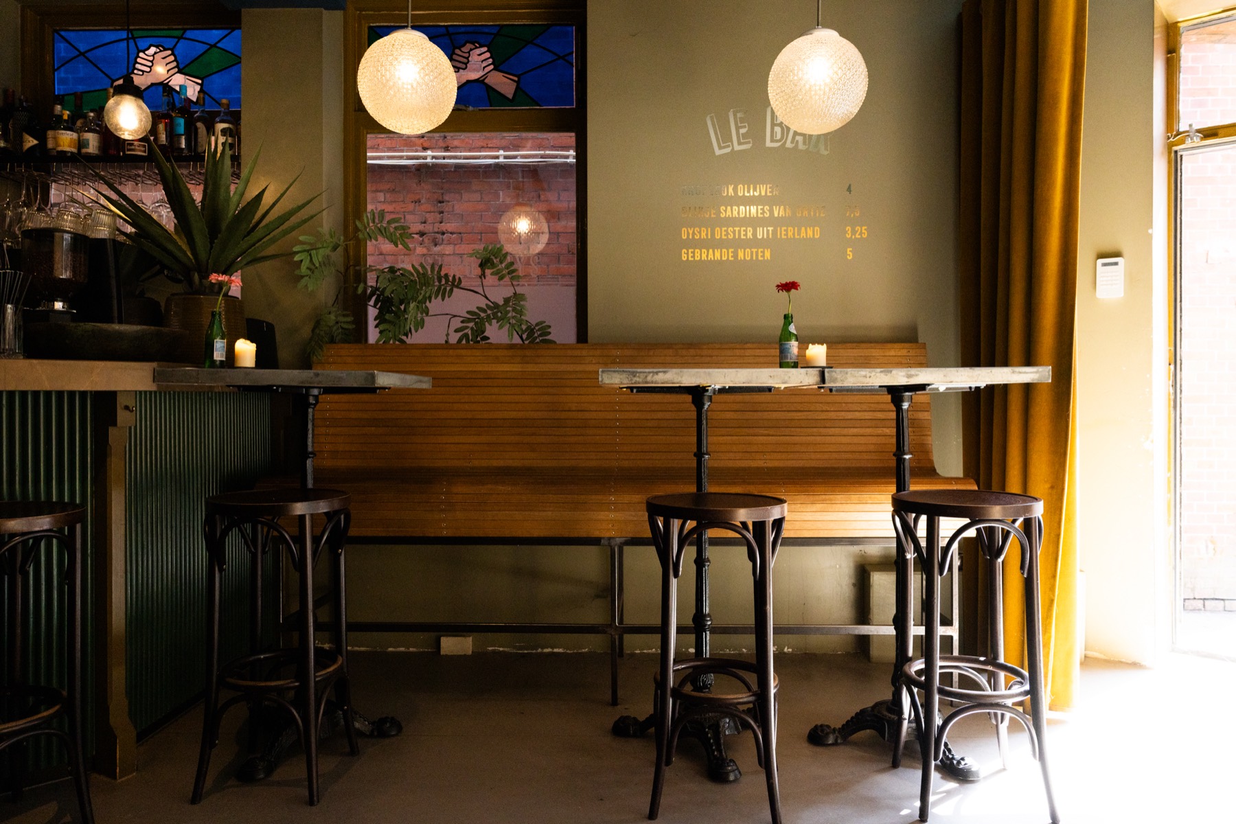 De bar met de houten bank, de lampen en het gele gordijn