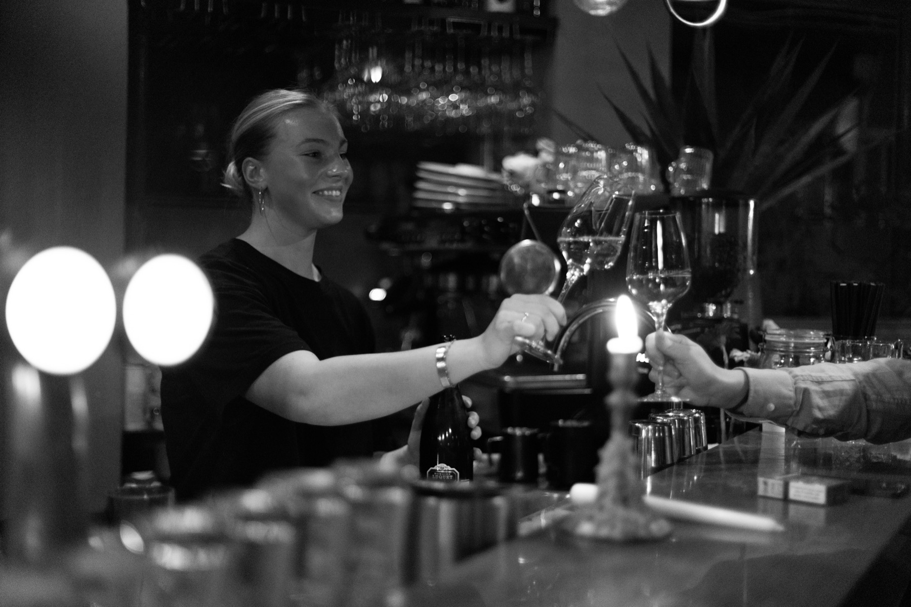 Een glas wordt lachend over de bar aangereikt