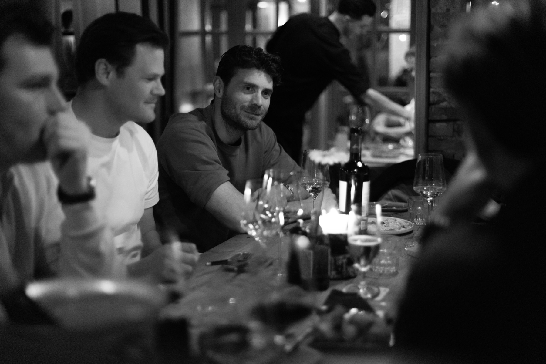 Een lange tafel vol gasten, glazen en borden